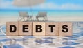 Debts on wooden cubes on relaxed beach background. Financial concept Royalty Free Stock Photo