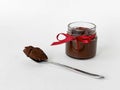 Decadent chocolate spread jar with red ribbon and spoon on white background Royalty Free Stock Photo