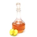 A decanter with apple cider vinegar and half a green apple isolated on a white background.