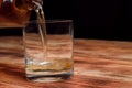 From a decanter, whiskey is poured into a glass