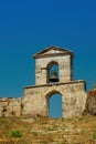 Decayed stone built bell tower with hanging bronze bell on top of a hill