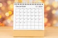 December 2024 desk calendar on wooden table with gold light bokeh background