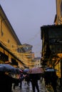 December 2021 Florence, Italy: Ponte Vecchio with people walking with umbrellas on a rainy day across shining window displays and