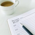 December 31, the last page of the diary and a pen and a cup of tea on white marble background , square. close up. Royalty Free Stock Photo