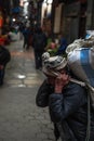 Kathmandu, Nepal - December 22: An unidentified man with a hat and leather jacket carries a heavy bag with his head on December 22