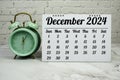 DECEMBER 2024 monthly calendar for planning and management concept with alarm clock on marble background