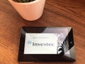 December 2019 Parma, Italy: Investec company logo icon on tablet screen close-up on wooden table. Investec visual brand