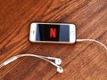 December 2019 Parma, Italy: Netflix company logo icon on smartphone screen close-up on wooden table with headphones. Netflix visua