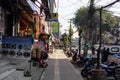 Pokhara, Nepal - December 2019: Unidentified people walks on the sidewalk, enters a shop and drives a motorbike on the street on