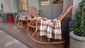 Wicker cozy armchair with blanket and small glass table outdoors. Plaid lies on the wicker furniture from rattan. Royalty Free Stock Photo