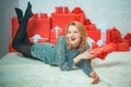 December surprise and party time. Young woman with Christmas present boxes in front of Christmas tree. Expressions face Royalty Free Stock Photo
