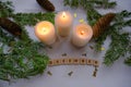 December text, christmas decoration with white burning candle, pine cones, tinsel, christmas tree branches on white background. To Royalty Free Stock Photo