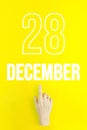 December 28th. Day 28 of month, Calendar date.Hand finger pointing at a calendar date on yellow background.Winter month, day of