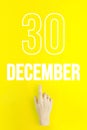 December 30th. Day 30 of month, Calendar date.Hand finger pointing at a calendar date on yellow background.Winter month, day of