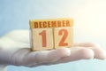 december 12th. Day 12 of month,Handmade wood cube with date month and day on female palm winter month, day of the year concept