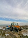 December 2018 - Wissant, France: Orange tractor towing a wooden white and blue fishing boat on a rocky beach during low tide Royalty Free Stock Photo