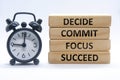 Decide, commit, focus, succeed text on wooden blocks with alarm clock on white cover background. commitment and business