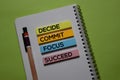 Decide. Commit. Focus. Succeed write on a sticky note isolated on office desk