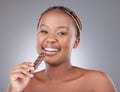 Decided to indulge. Studio shot of an attractive young woman eating a slab of chocolate against a grey background.