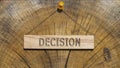Decision word. Written on wooden rectangular frame surface. Background log surface.