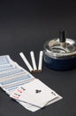 Deck of cards and three cigarettes spilled on the black background Royalty Free Stock Photo