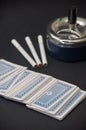 Deck of cards and three cigarettes spilled on the black background Royalty Free Stock Photo