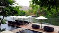 Deck chair or daybeds and umbrellas on waterfront raft in resort near river Kwai Kanchanaburi, Thailand.