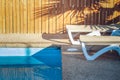 Deck chair rustic resort yard space of motel lounge furniture near swimming pool side under palm shadows on wooden palisade