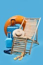 Deck chair, suitcases and beach accessories on light blue background. Summer vacation Royalty Free Stock Photo