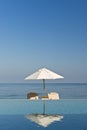 Deck chair and umbrella next to infinity pool
