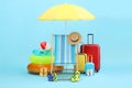 Deck chair, umbrella, suitcases and beach accessories on light blue background. Summer vacation Royalty Free Stock Photo