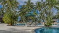 Deck chairs with soft mattresses and sun umbrellas are located by the swimming pool with clear turquoise water. Royalty Free Stock Photo