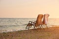 Deck chairs with towels on backrest on the seashore. Royalty Free Stock Photo