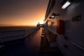 Deck of ferry sailing across the sea during last moments of a beautiful sunset with arriving land in the background. Concept of Royalty Free Stock Photo