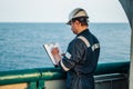 Deck Officer on deck of offshore vessel or ship , wearing PPE personal protective equipment. He fills checklist Royalty Free Stock Photo