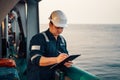 Deck Officer on deck of offshore vessel or ship , wearing PPE personal protective equipment. He fills checklist Royalty Free Stock Photo