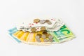 A deck of playing cards with coins lies on a stack of banknotes and coins of new Israeli shekels - NIS - on a white background