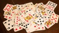 deck of playing cards such as poker or rummy, randomly scattered on a dark brown wooden game table