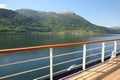 Deck of a ship as it cruises down the beautiful fjord with mountains & villages along the water, Hardangerfjord, Norway Royalty Free Stock Photo