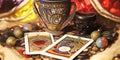 A deck of tarot cards is on a table with a cup and a bowl. The cards are arranged in a way that they are facing the viewer, and Royalty Free Stock Photo