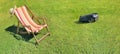 Deckchair on greenery grass and robotic lawnmower