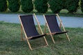 Deckchairs in autumn garden. Two deckchairs on summer green lawn. Lounge sunbed. Wooden garden furniture on grass lawn outdoor for