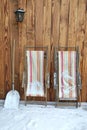 Deckchairs folded and placed against a wooden wall covered with snow Royalty Free Stock Photo
