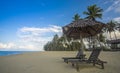 Deckchairs under the thatched roof on a beach, a tourist destination in Terengganu, Malaysia. Clean sandy beach with blue sea and