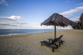 Deckchairs under the thatched roof on a beach, a tourist destination in Terengganu, Malaysia. Clean sandy beach with blue sea and