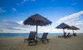 Deckchairs under the thatched roof on a beach, a tourist destination in Terengganu, Malaysia. Clean sandy beach with blue sea and