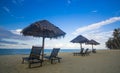 Deckchairs under the thatched roof on a beach, a tourist destination in Terengganu, Malaysia. Clean sandy beach with blue sea and