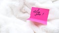 touching message I love you on pink postcard on white fluffy blanket. Details of cozy bedroom, morning for a loved one