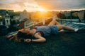 Beautiful woman rests on the roof view from the back, sunset time, city, rest time, light, hipster photo, brunette hair Royalty Free Stock Photo