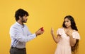 Declining proposal. Indian woman refusing to take engagement ring rejecting boyfriend, standing over yellow background Royalty Free Stock Photo